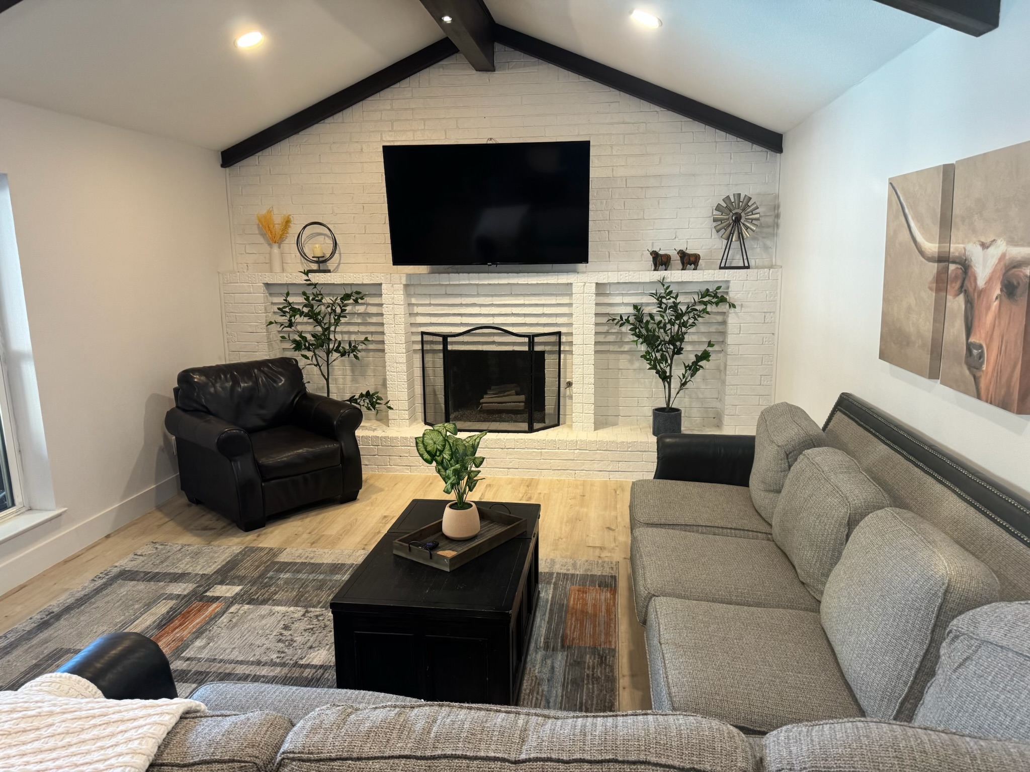 Remodeled living room with white-painted brick fireplace and wood floor